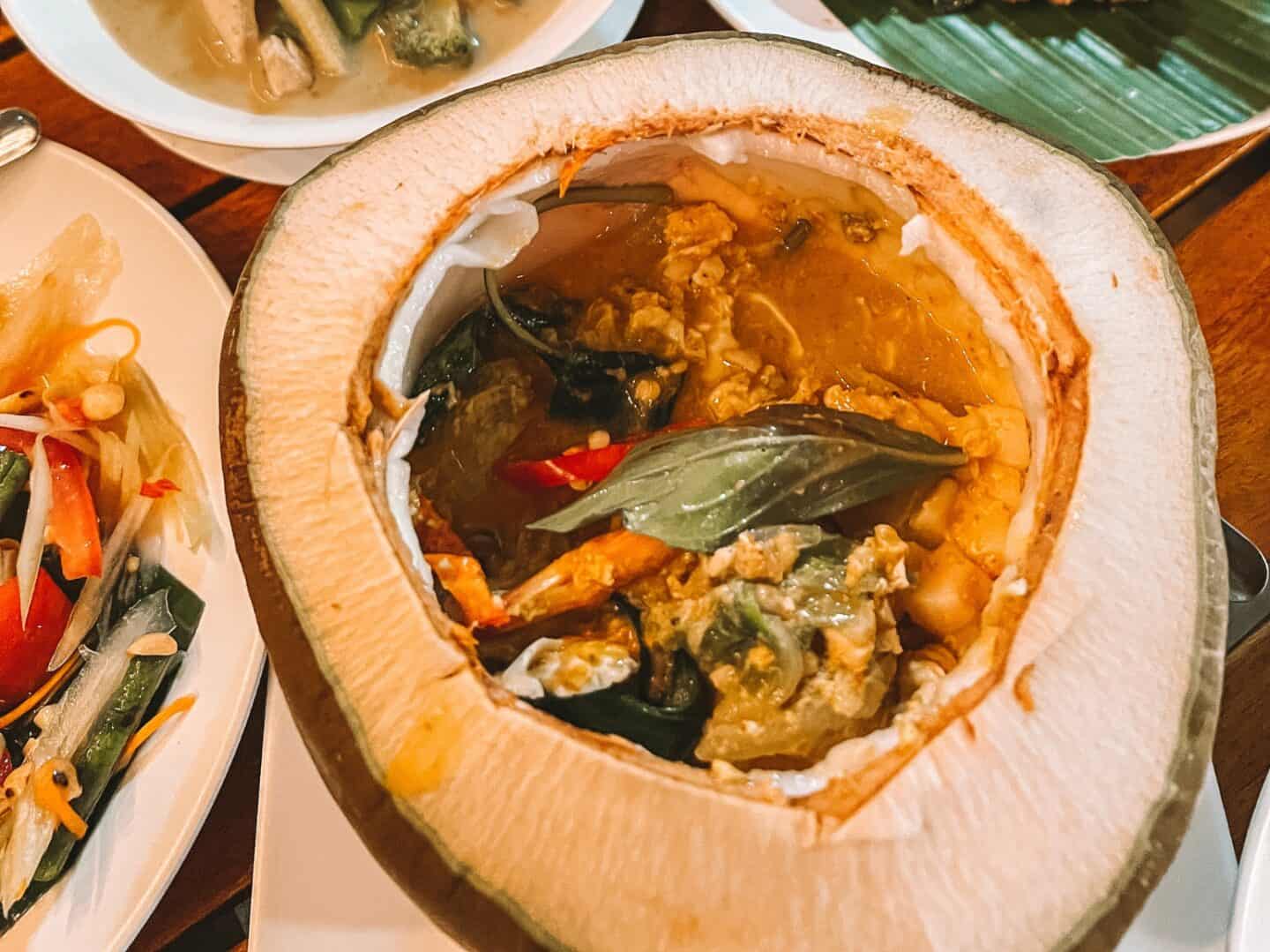 Hor mok ma prow awn, or seafood curry, served in a fresh coconut in Krabi Thailand