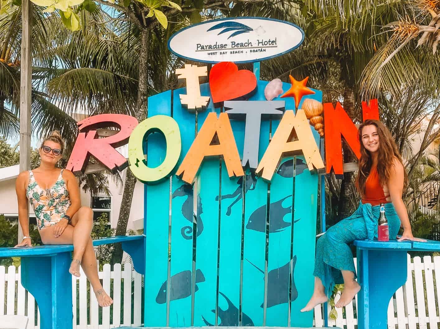 My friend and I on a huge beach chair with an I love Roatan sign