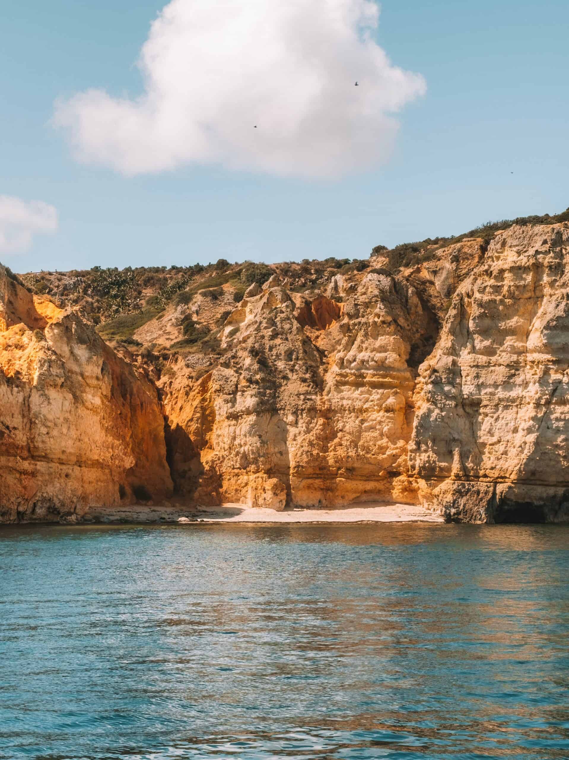 A hidden beach framed by sandstone cliffs and blue ocean. 