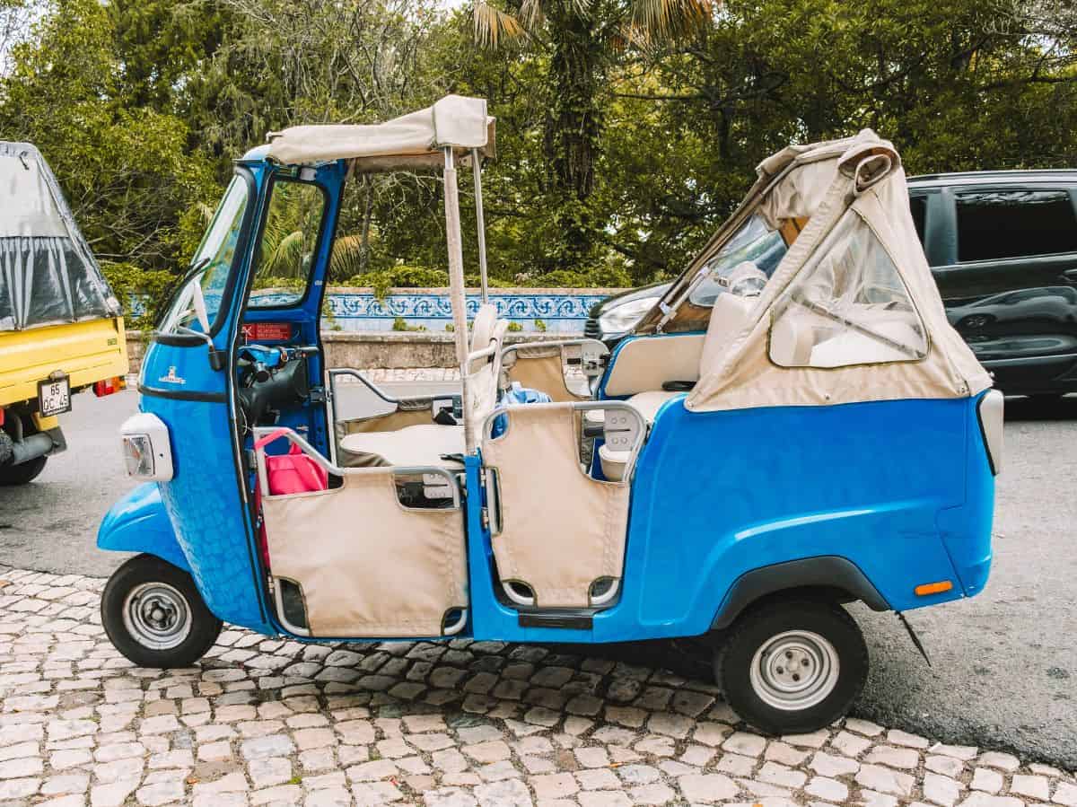 A blue tuk tuk parked on the street. Is Lisbon worth visiting? A fun and breezy tuk tuk tour might convince you that the answer is yes. 