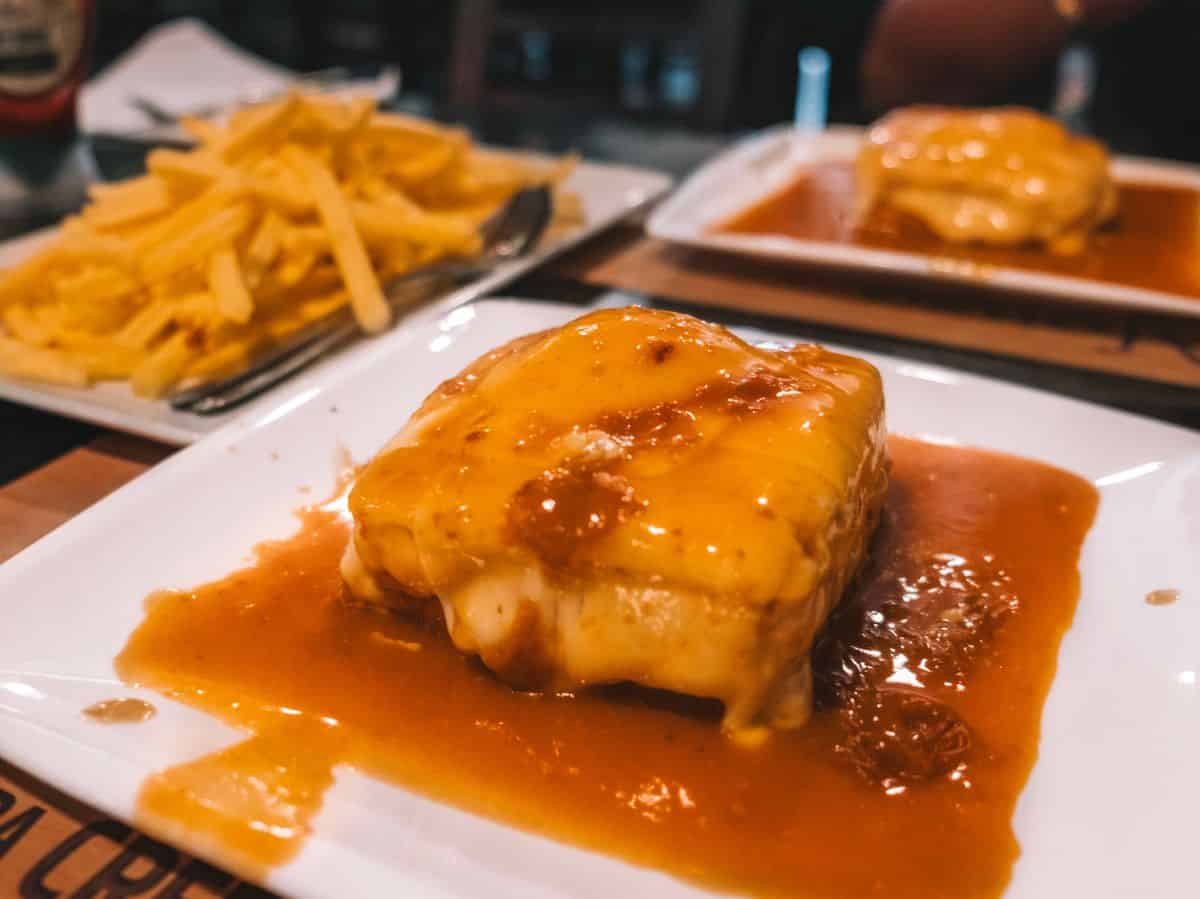 A glorious Francesinha from O Afonso in Porto—it's smothered in melted cheese and spicy sauce. This is definitely one of the traditional Portuguese foods you don't want to miss. 