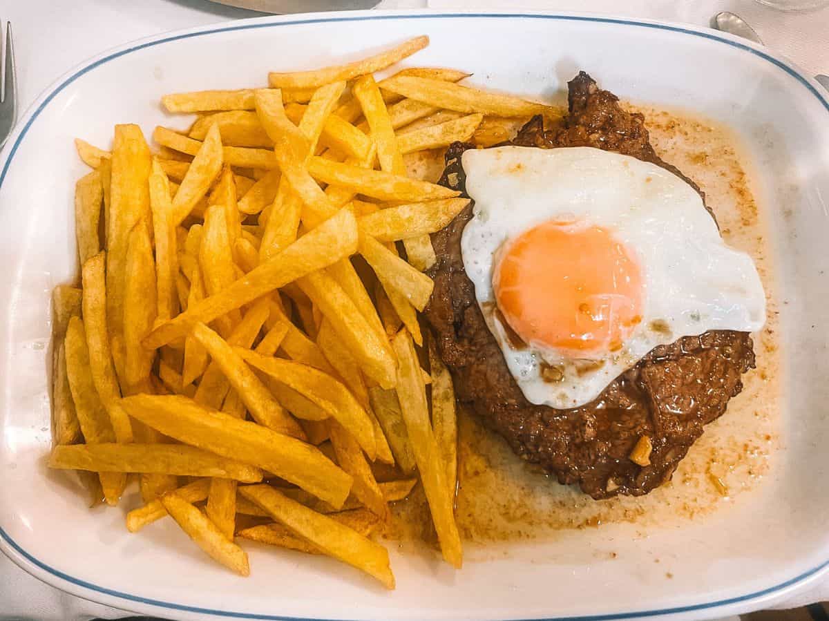 Bitoque topped with a fried egg and served with french fries. This is one of the traditional Portuguese foods you don't want to miss. 