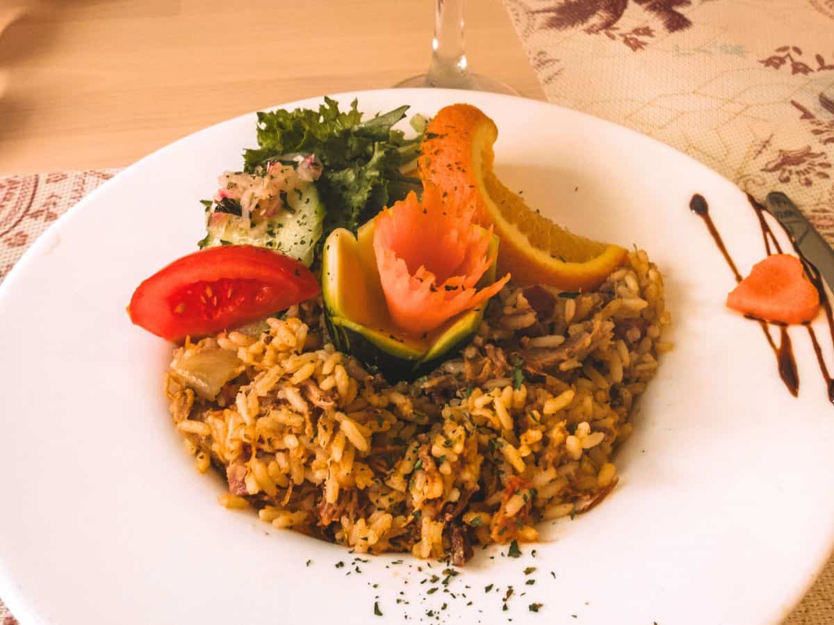 A heaping plate of duck rice (arroz de pato) with fresh veggies and an orange wedge from Rustikus restaurant in Funchal. 