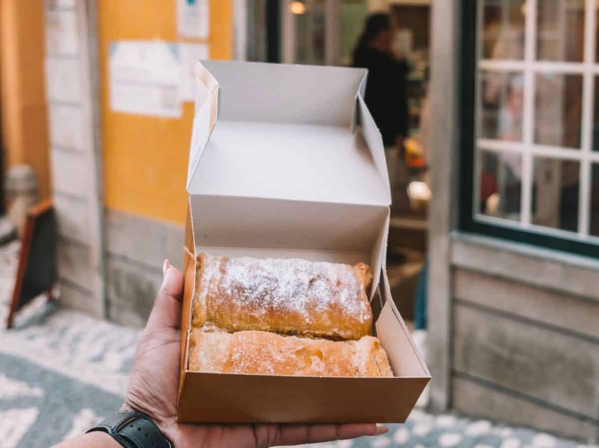 Two travesseiro, or "pillow cakes" being held up in the box in front of Casa Piriquita in Sintra. These pastries are definitely one of the traditional Portuguese foods you can't miss. 