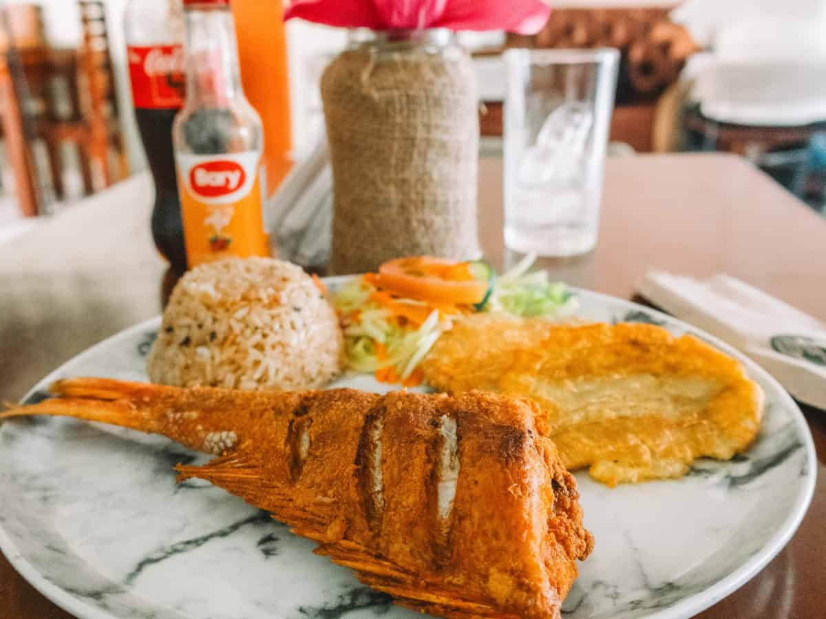 A plate piled high with deep fried red snapper, mashed and fried plantains, coconut rice, and salad from Ancora Steakhouse—one of the best restaurants in Santa Marta, Colombia.