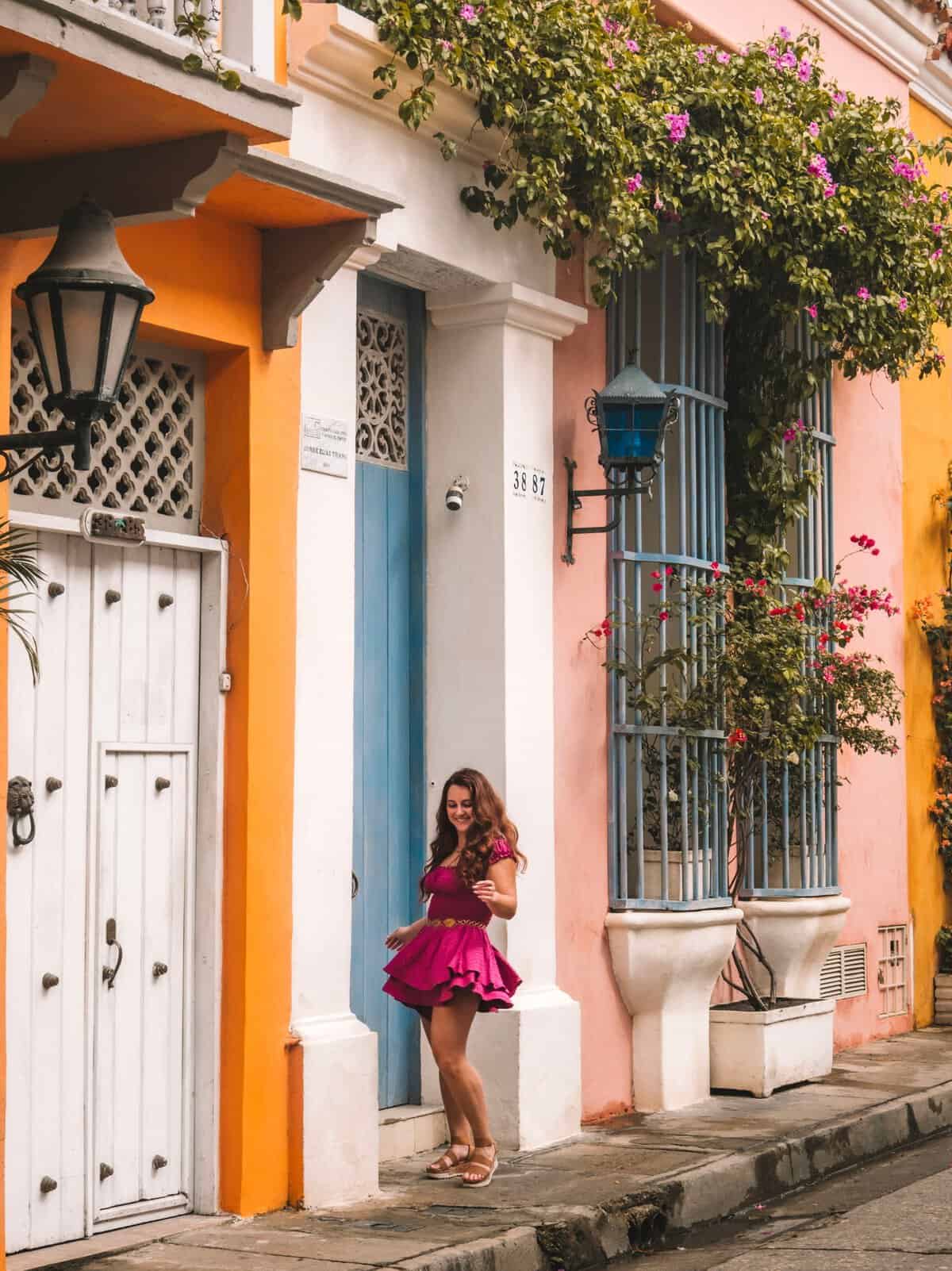 Me next to a blue door and pink flowers on the streets of Cartagena.